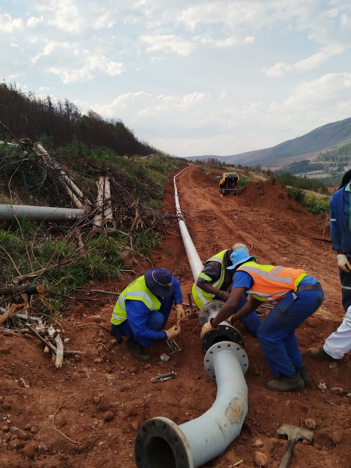Crew installing a flanged slurry pipe bend on an overland mining pipeline