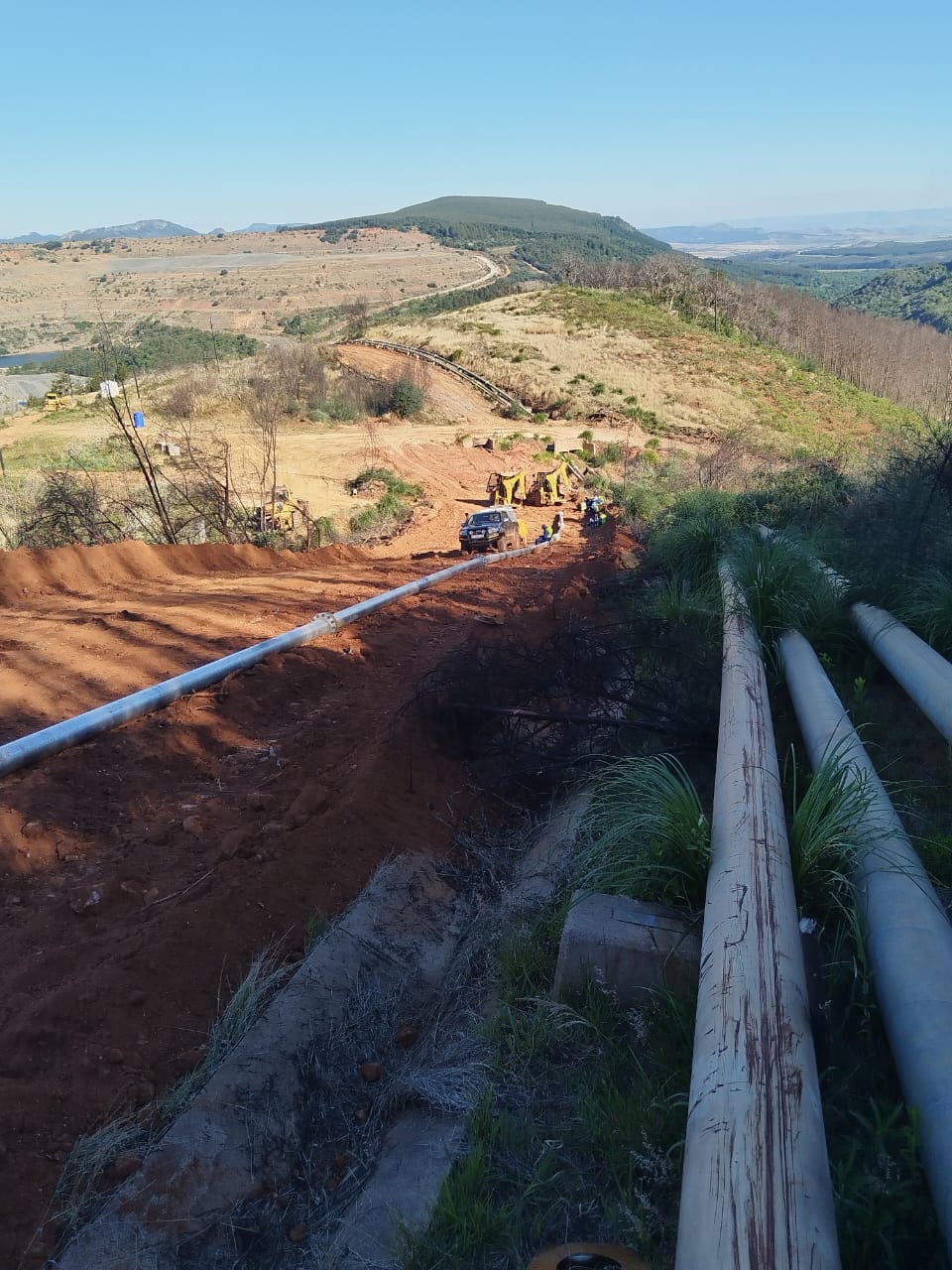 Overland slurry pipeline descending a mining hillside toward the plant